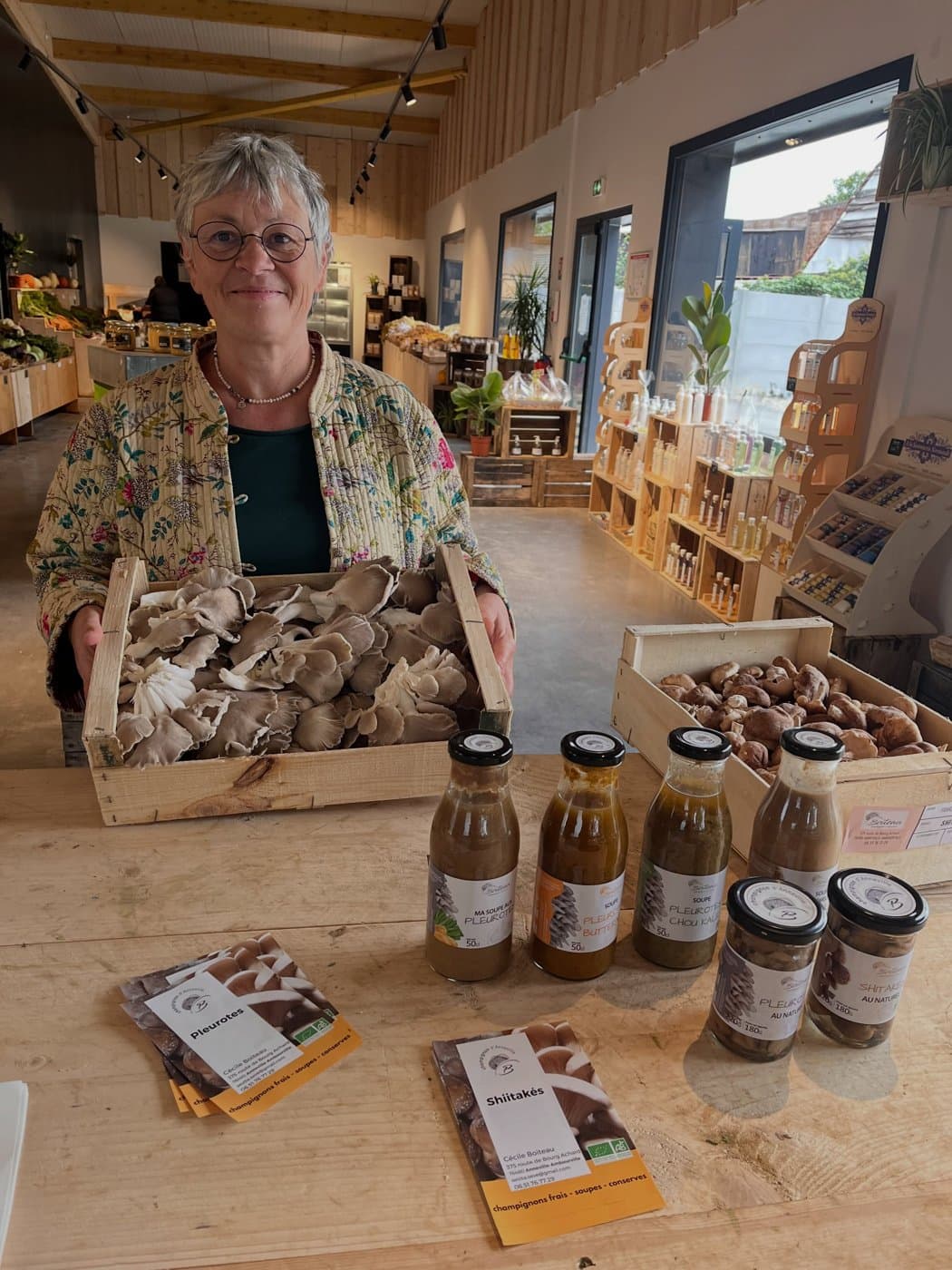 Céline, productrice, derrière une cagette de pleurotes, avec ses soupes et bocaux de champignons